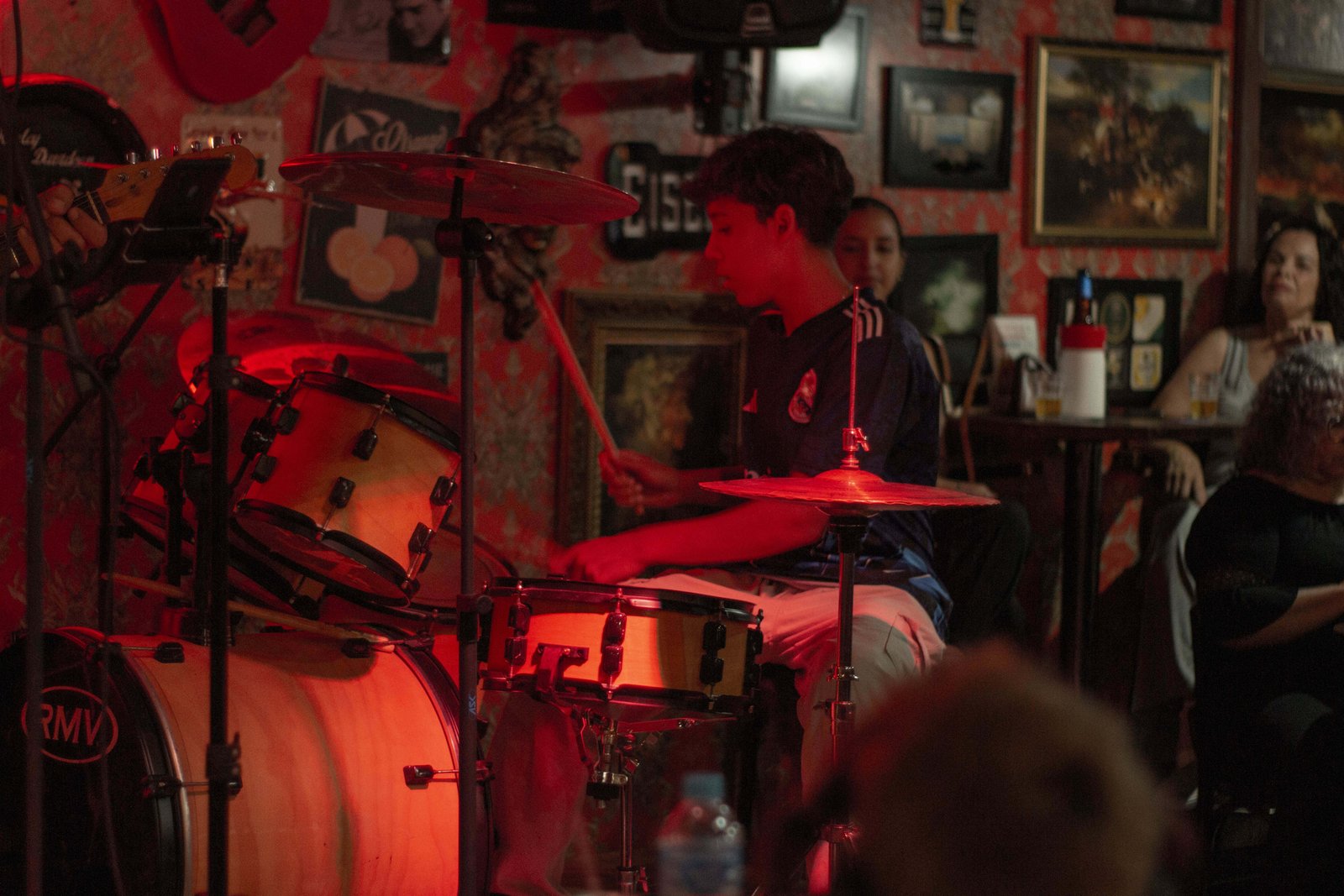 Baterista no palco com outros alunos de música tocando em uma apresentação no centro de Londrina.